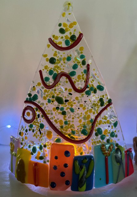 Charlestoncraftsgallery Cordelia Story lighted Christmas tree with presents table top.jpeg