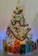 Charlestoncraftsgallery Cordelia Story lighted Christmas tree with presents table top.jpeg